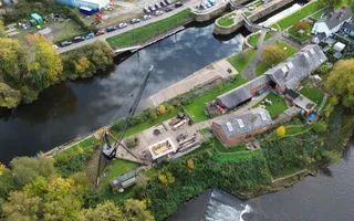 Drone photo of a canal with crane on the bank and old brick buildings