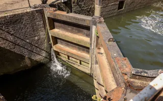 Looking down onto the wooden lock gate which has water spurting out the side.