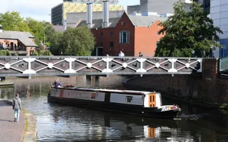 A narrowboat passes under an iron bridge in central Birmingham.