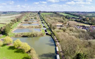 Aerial view of a flight of locks, each with large overflow pounds next to them, surrounded by fields.