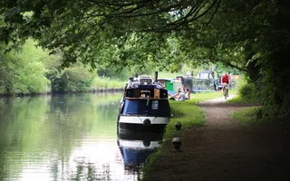 Idyllic canal scene, reflections on water, cyclists people sitting down enjoying the canal