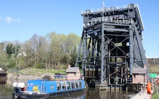 A blue trip boat lines up to enter a water tank at the bottom of Anderton Boat Lift, a large metal boat lift.