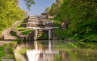 Looking up at five steep staircase locks bathed in sunlight and surrounded by vibrant greenery.