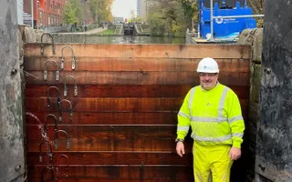 Man in high vis and hard hat standing in a drained canal infront of new lock gates