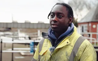 Apprentice engineer standing by canal wearing yellow coat