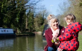 A woman and child smile on the towpath with boats in the canal