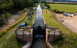 Ariel shot of a lock on a sunny day with fields running alongside