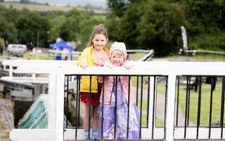 two children standing on a bridge smiling at camera.
