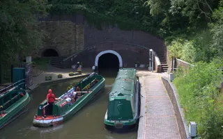 A narrowboat approaches a very low tunnel with white paint around its entrance