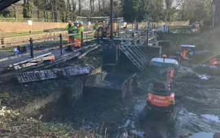 Digger in a canal removing silt with working and crane to the left