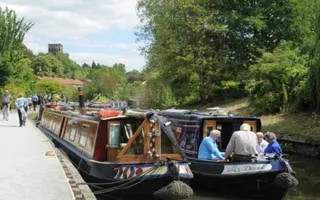 Group sat on moored narrowboat in Vines Park with people walking by on towpath