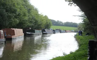 View of Middlewich Branch under bridge with moored boats and anglers on the towpath