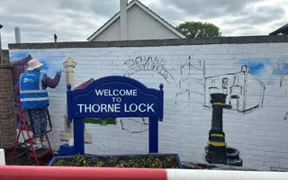 Volunteer in blue high vis painting on a wall