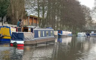 A narrowboat passes moored boats on a busy stretch of the canal