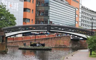 Iron bridge over the canal at a three-way junction, in front of high-rise buildings and Sea Life Centre.
