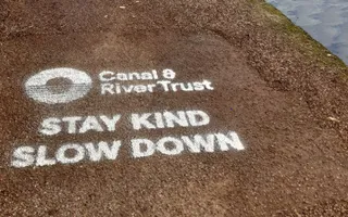 The words 'stay kind slow down' printed on the towpath