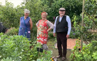 three people smiling towards the camera in the gardens at Ellesmere, dressed in period costumes