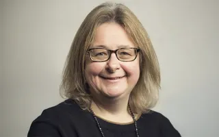 Headshot of a woman in a black top and wearing glasses