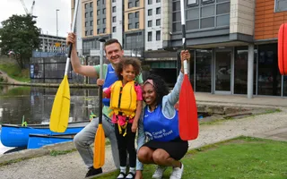 A family with one child holding paddles in the air and smiling