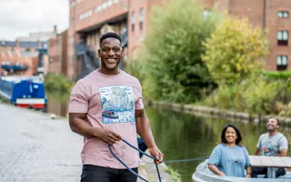 Man smiling to camera holding rope on a towpath with people in the background smiling