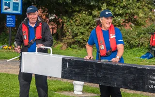 Two Canal & River Trust volunteers open a lock gate
