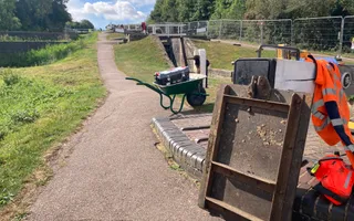 Whhel barrow on the towpath with tools and PPE to the right