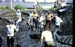 Vintage photo of adults and children digging in the mud