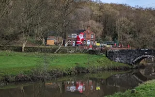 An inflatable Santa stands in a pub garden in front of the idyllic, rural Caldon Canal.