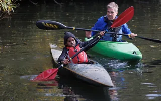 A boy and instructor on the water paddling canoes