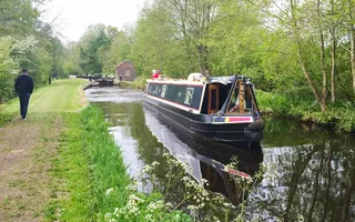 Person walking alongside the canal with a narrowboat on it