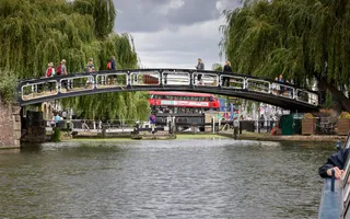 Arched bridge over canal with red london bus in the background