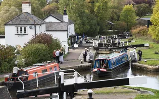 Two boats passing through a flight of locks with a group of people watching from the towpath