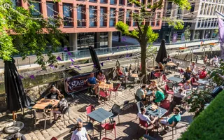 Wide shot of a beer garden nect to a canal on a sunny day