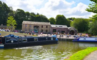 On a sunny day a narrowboat 'Yorkshire Bourne' turns the corner of a canal