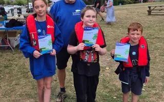Group of children wearing lifejackets holding up leaflets