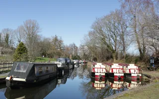 Narrowboats moored on both sides of the rural canal at Goytre Wharf.
