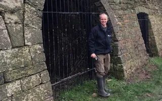 Ecologist stands outside metal bars on a lime kiln