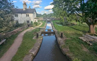 A single lock with a small lock-side cottage with a blue sky high above.
