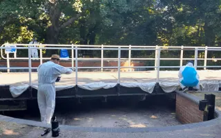 Two people painting railings on the canal