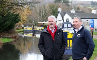 Two men standing next to a canal