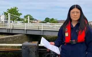 A woman standing next to lock gates on the canal