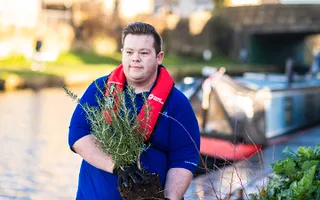 A volunteer plants flowers next to the canal