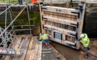 workers tending to new lock gate in drained canal