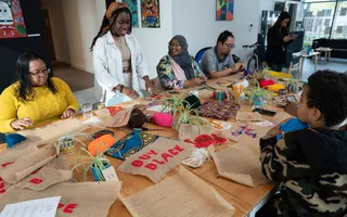 A group of people in a room making textile art on a large table