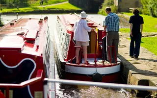 One boat leaving a lock while the other waits; people walk along the towpath
