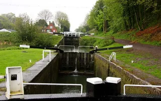 Empty lock below a flight of locks, lined by trees along the towpath.