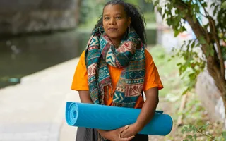 A woman with a yoga mat by the canal