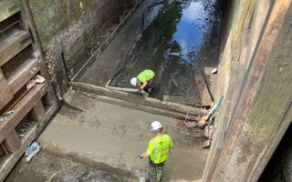 Two workers at the bottom of a drained lock