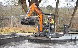 A mechanical crane on the water scoops large amounts of waste from the canal.