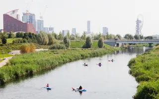 Group of kayakers on quiet stretch of the Bow Back Rivers with urban cityscape in background